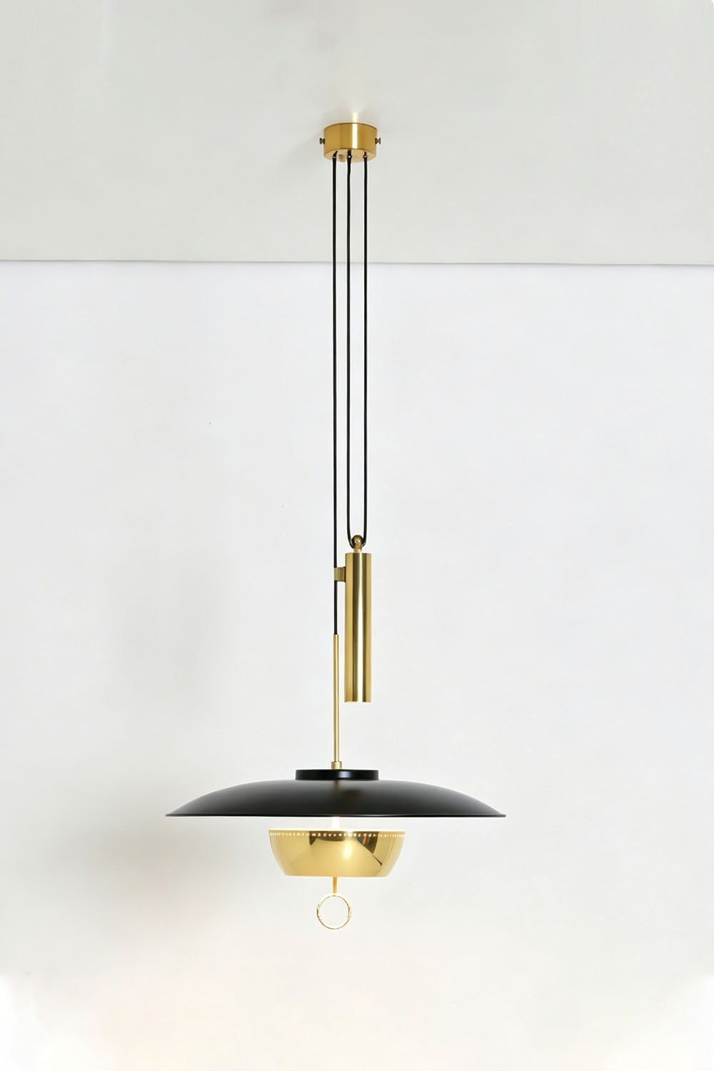 Adelaide Saucer Brass Pendant Light hanging from the ceiling with sleek black and gold design.