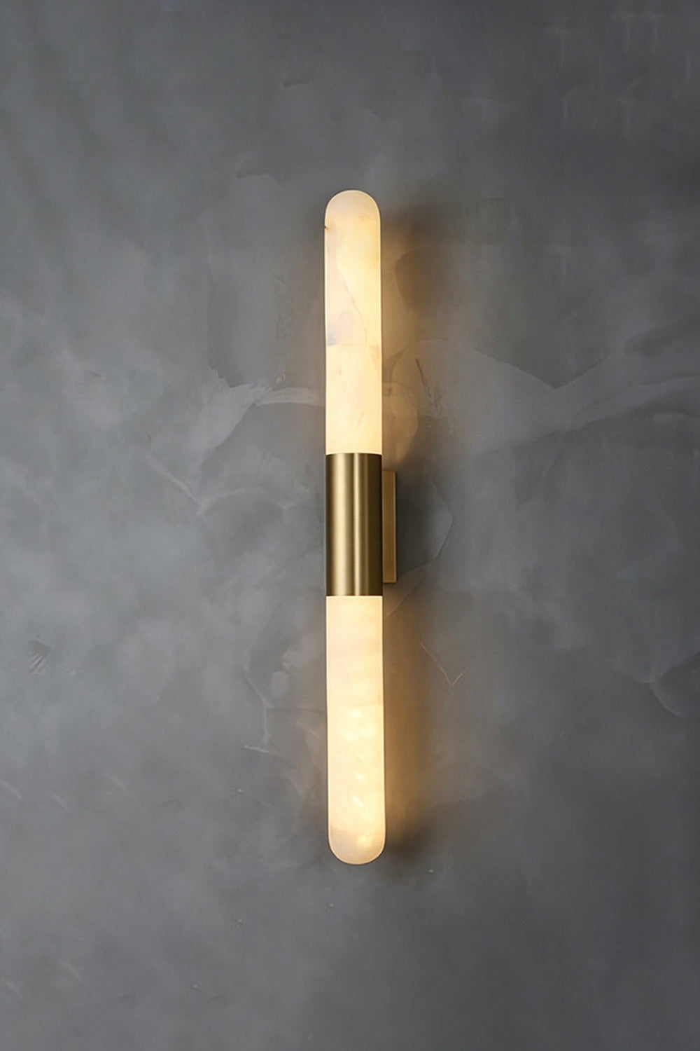 Corin Linear Alabaster Wall Sconce on a gray wall, featuring a warm glow from the alabaster and gold-toned frame.