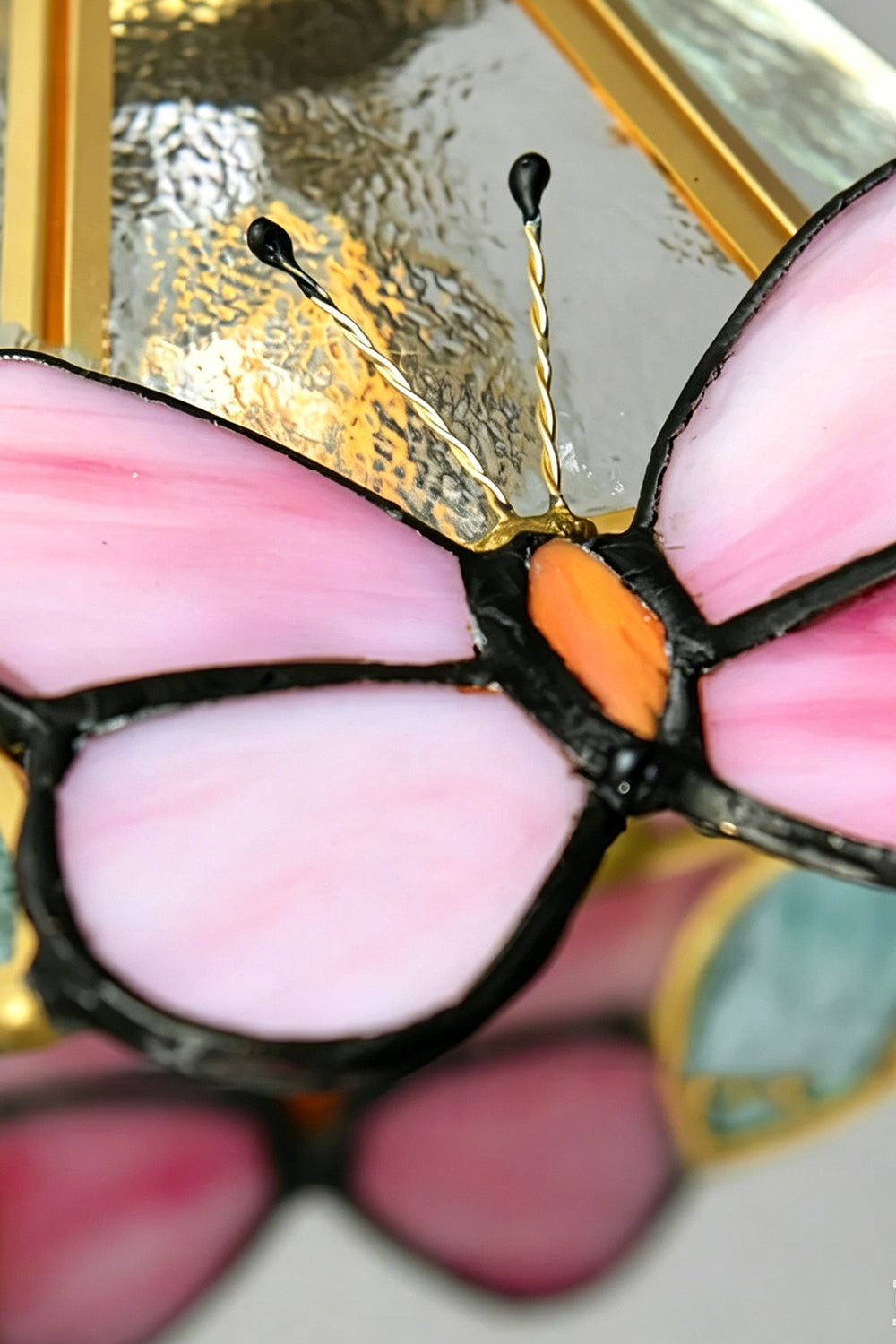 Iris Butterfly Stained Glass Wall Lamp | Stained Glass, Metal, Wood | Macro close-up shot highlighting the vibrant pink and orange stained glass panels, leaded solder lines, and delicate wire antennas of the butterfly motif | Detail shot | vexa lamps