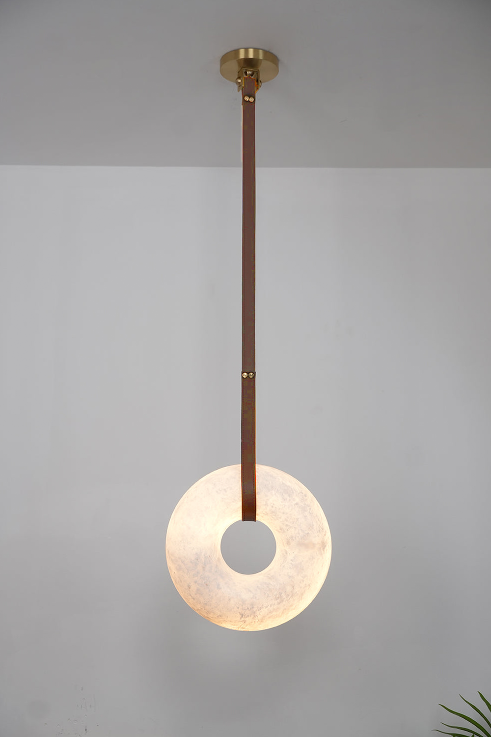 Nerissa Alabaster Ring Leather Pendant Light | Natural Alabaster, Leather and Brass | Single-strap disc variant full view hanging on a plain backdrop | vexa lamps