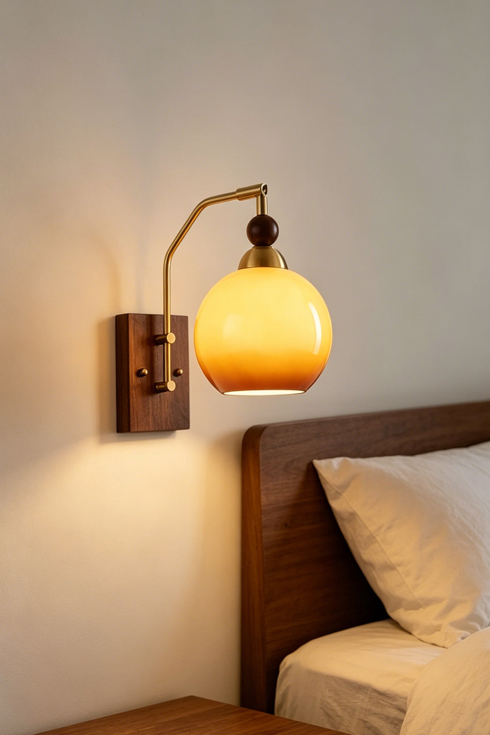 Vesper Caramel Gradient Wall Lamp | Glass, Metal, Wood | Bedside perspective of the wall sconce casting a warm, comforting light directly over a white pillow setup | vexa lamps