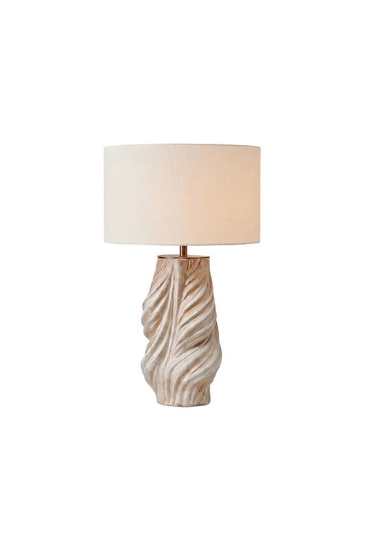 Adara Sculptural Ceramic Table Lamp | Ceramic, Fabric | Isolated lit product shot of a contemporary table lamp featuring a highly textured, twisted wavy ridged cream ceramic base and a minimalist white drum fabric shade | White background | vexa lamps