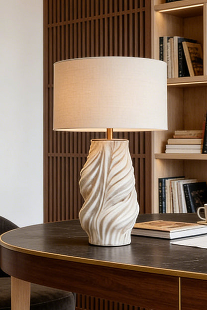 Adara Sculptural Ceramic Table Lamp | Ceramic, Fabric | Staged nicely on a dark polished oval wood desk or boardroom table near a vertical wood slat wall divider | vexa lamps