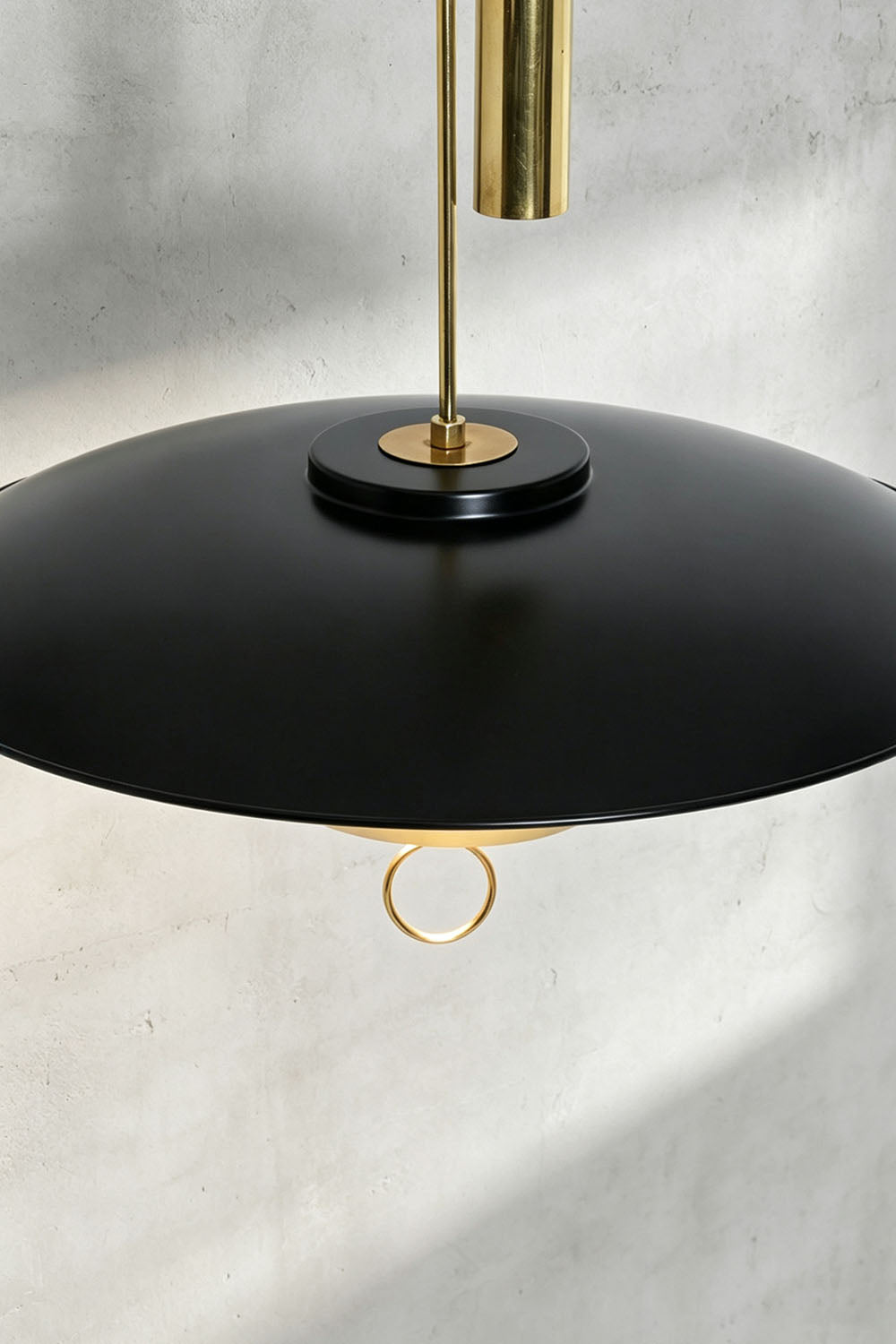 Adelaide Saucer Brass Pendant Light with a sleek black shade and gold accents, perfect for modern interior lighting.