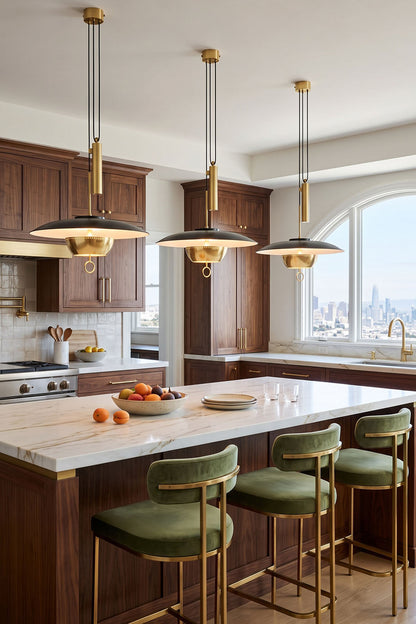 Adelaide Saucer Brass Pendant Light illuminating a modern kitchen with stylish green bar stools and marble countertop.