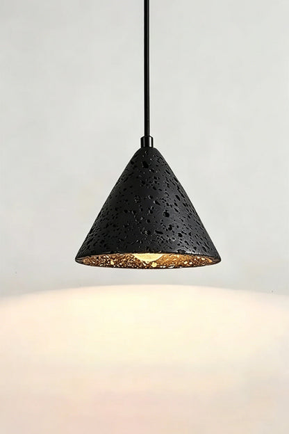 Lit Aethel Core Pendant Light | Black Travertine, Metal | Wall view showing textured stone and illumination | vexa lamps