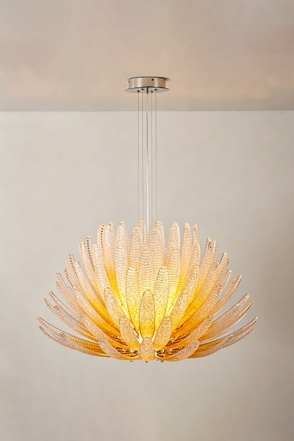 Helios Agave Glass Starburst Chandelier | Glass, Metal | Amber glass variant lit against a light neutral wall, showing its warm golden tones | Isolated shot | vexa lamps