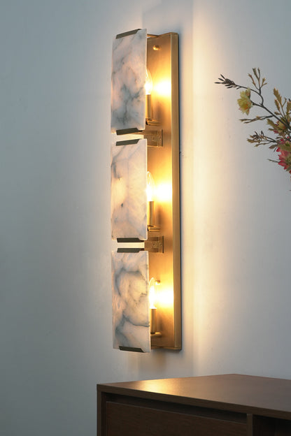 Side view of lit 3-panel alabaster wall lamp | Brass, Alabaster | Showing warm light diffusion against wall | vexa lamps