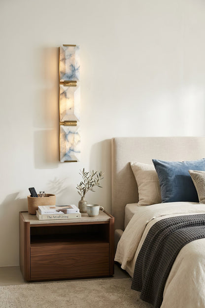Vertical 3-panel alabaster wall sconce | Brass, Alabaster | Installed in a bedroom above a wooden nightstand | vexa lamps