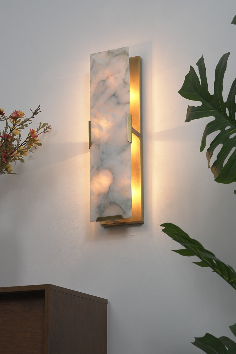 Lit alabaster wall lamp with 3-tier design | Brass, Alabaster | Side perspective view in a living room near plants | vexa lamps
