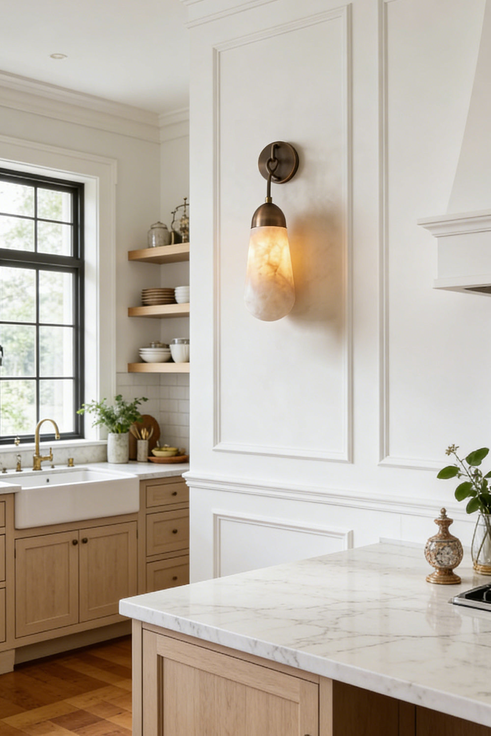 Alabaster Teardrop Wall Sconce illuminating a modern kitchen with natural wood cabinets and marble countertops.