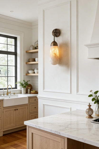 Alabaster Teardrop Wall Sconce illuminating a modern kitchen with natural wood cabinets and marble countertops.