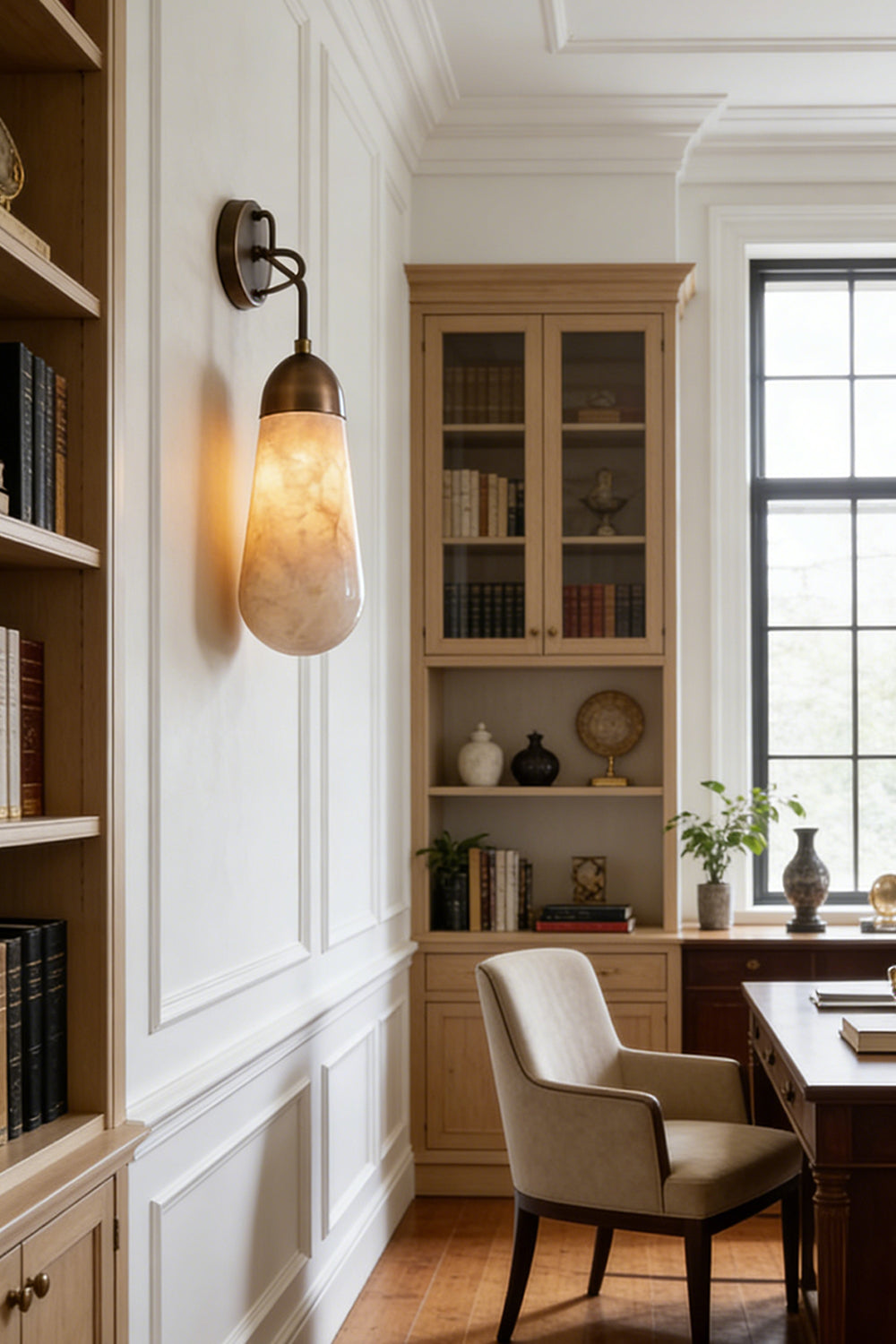 Alabaster Teardrop Wall Sconce illuminating a stylish office with bookshelves and a desk.