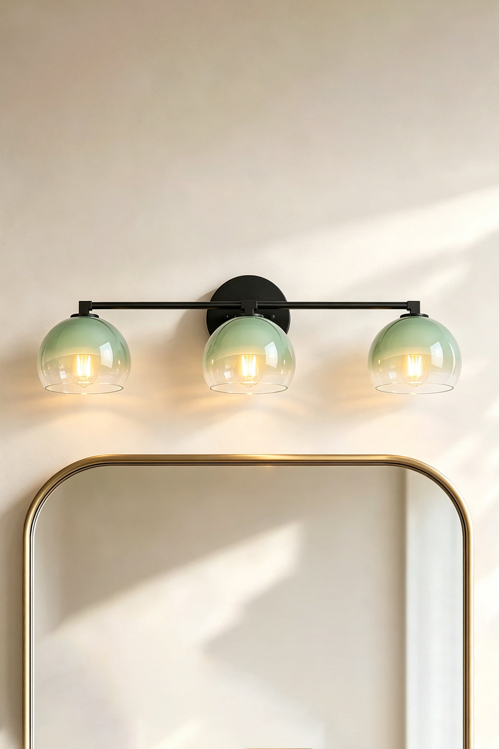 Alba Ombre Glass Wall Sconce with green glass globes above a round mirror on a light wall.