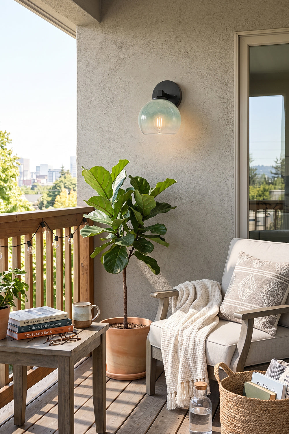 Alba Ombre Glass Wall Sconce illuminating a balcony with plants and outdoor furniture.