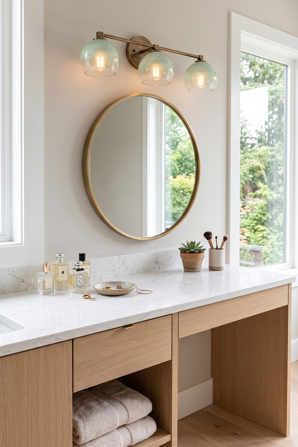 Alba Ombre Glass Wall Sconce above a round mirror in a bathroom vanity setting.