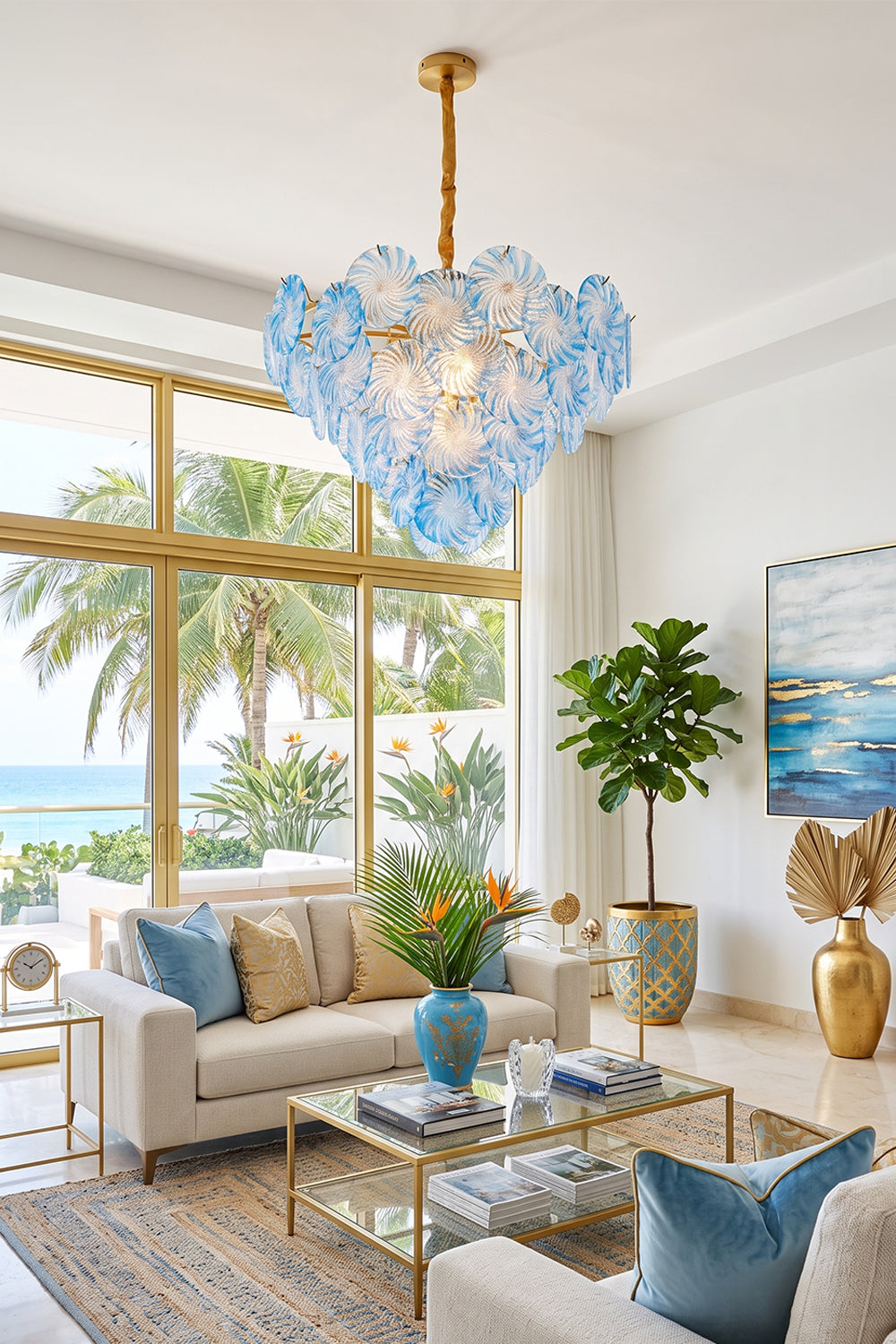 Amara Pink Glass Petal Chandelier | Coastal Living Room | The light blue petal chandelier casting a soft glow in a spacious tropical lounge area with palm tree window views | vexa lamps