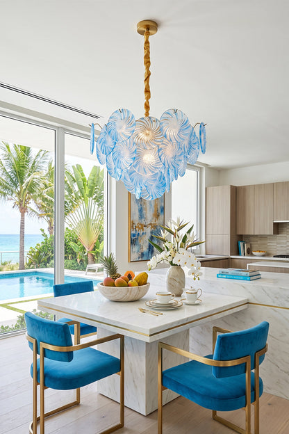 Amara Pink Glass Petal Chandelier | Dining Room Light | The sea-blue glass variant hanging elegantly over a modern white dining table paired with bright blue velvet chairs in a coastal home | vexa lamps