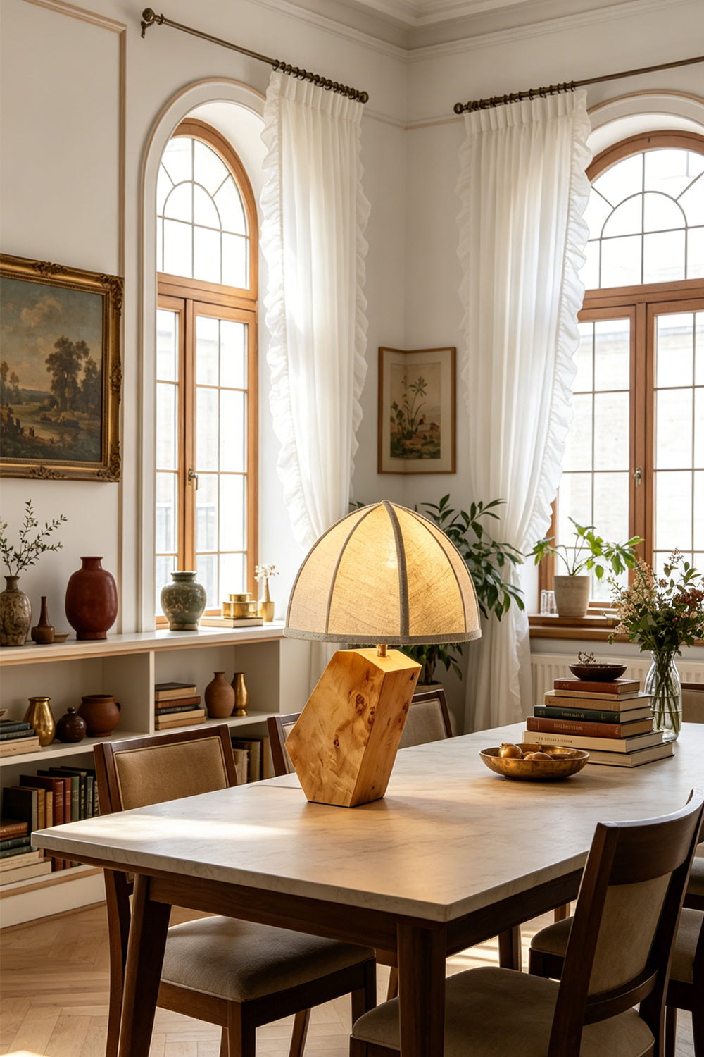 Angolo Canted Faceted Wood Table Lamp | Wood, Fabric, Metal | Placed on a large wooden dining table in a rustic dining room with arched windows and bookshelves | vexa lamps