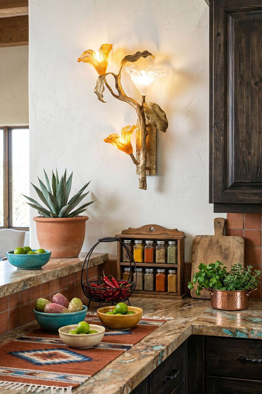 Arboreal Bloom Brass Wall Lamp | Brass, Glass | The Arboreal Bloom brass wall lamp positioned on a textured wall above a rustic fireplace mantel with a distressed mirror, an eclectic orange sofa, and diverse potted plants | Lifestyle in-situ shot | vexa lampsArboreal Bloom