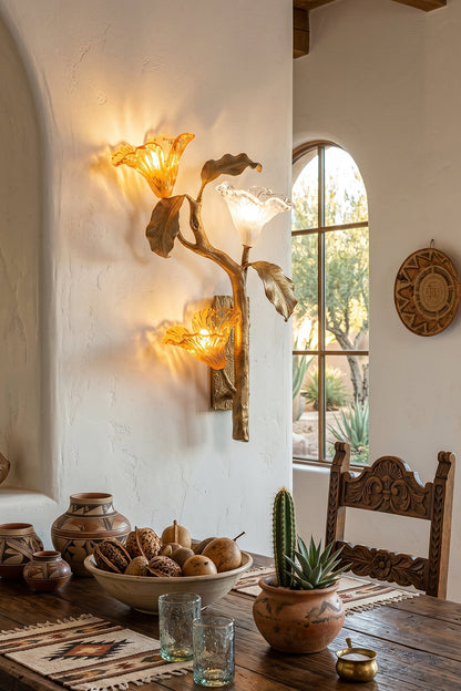 Arboreal Bloom Brass Wall Lamp | Brass, Glass | The Arboreal Bloom brass wall lamp mounted next to a bed with patterned textiles, a carved wooden nightstand, and desert art in a rustic bedroom | Lifestyle in-situ shot | vexa lampsArboreal Bloom