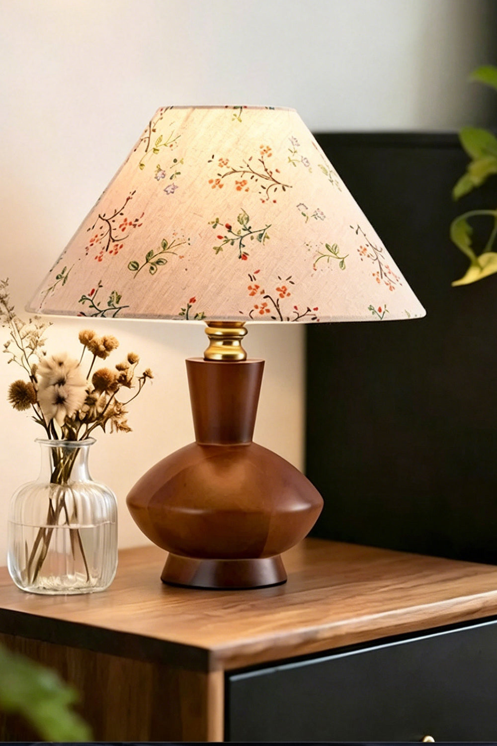 Arboreal Canopy Walnut Table Lamp on a wooden bedside table with a floral fabric shade and decorative vase.