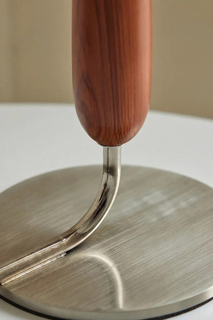 Arden Walnut Floor Lamp | Wood, Metal, Fabric | Macro structural view showing the curved metallic neck pipe connecting the walnut wood stem to the circular brushed metal base plate | Detail shot | vexa lamps