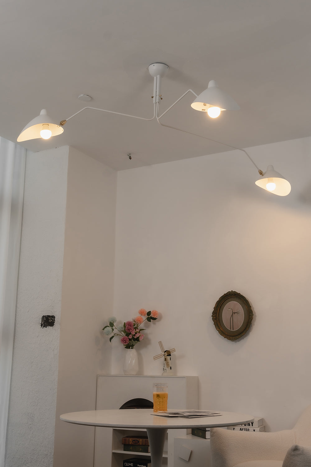 Lit white 3-arm articulated spider light | Metal | Interior mood shot above a round dining table | vexa lamps