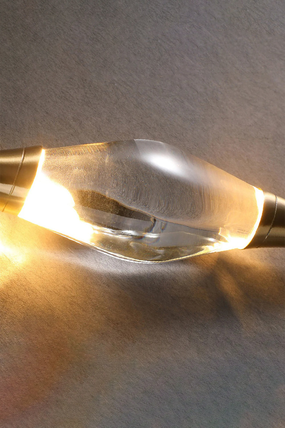 Astraea Crystal Linear Wall Sconce | Crystal, Brass | Close-up illuminated view focusing on the warm light refracting and reflecting through the thick faceted clear crystal center | Detail shot | vexa lamps