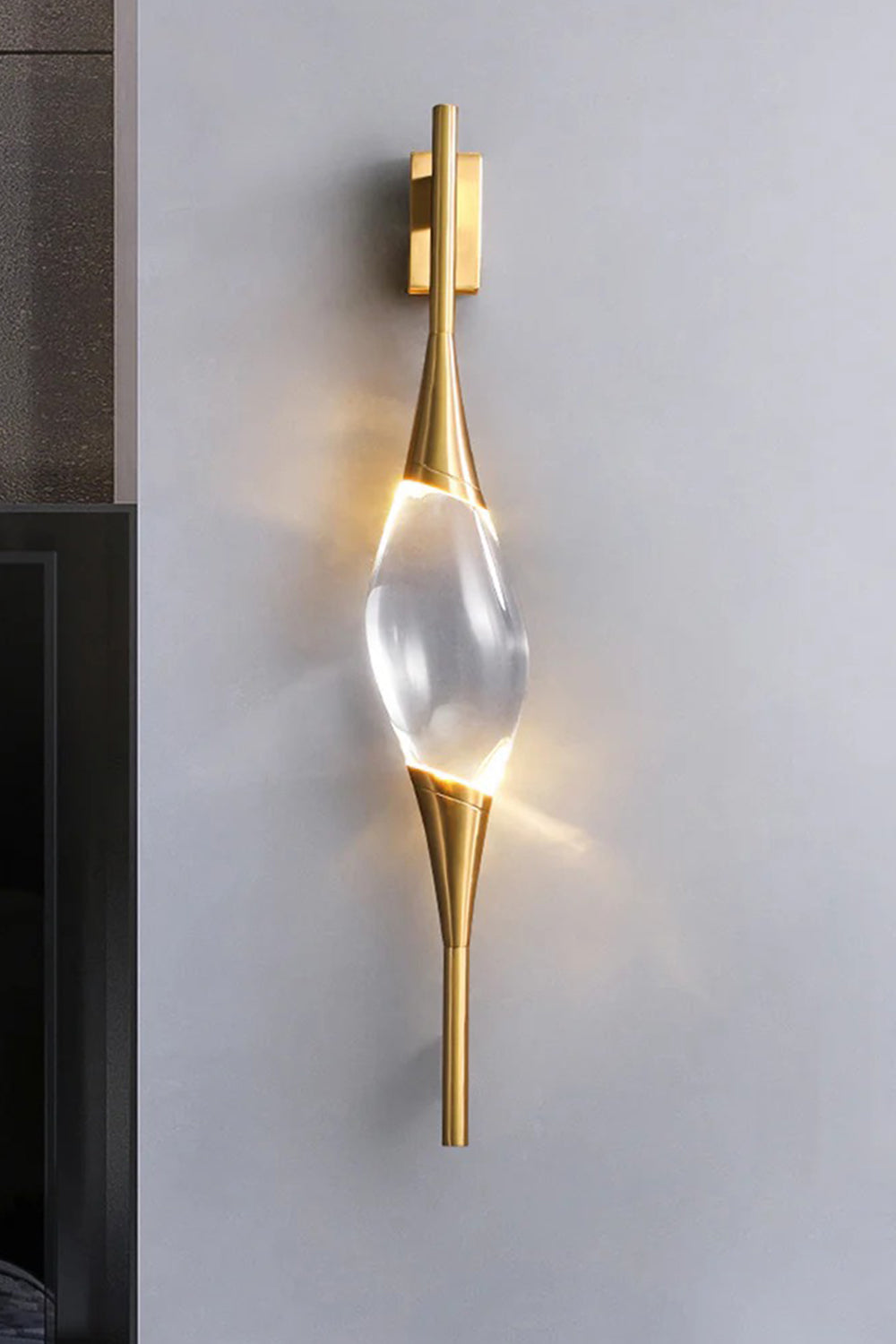 Astraea Crystal Linear Wall Sconce | Crystal, Brass | Studio view of the fully lit linear crystal sconce casting an elegant bow-tie shaped warm light halo on a light grey wall | vexa lamps