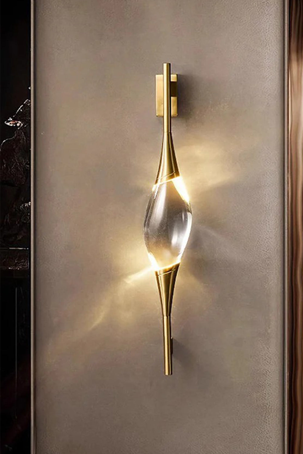 Astraea Crystal Linear Wall Sconce | Crystal, Brass | Staged studio shot of the illuminated golden wall lamp radiating a bright warm glow against a dark brown textured background | vexa lamps
