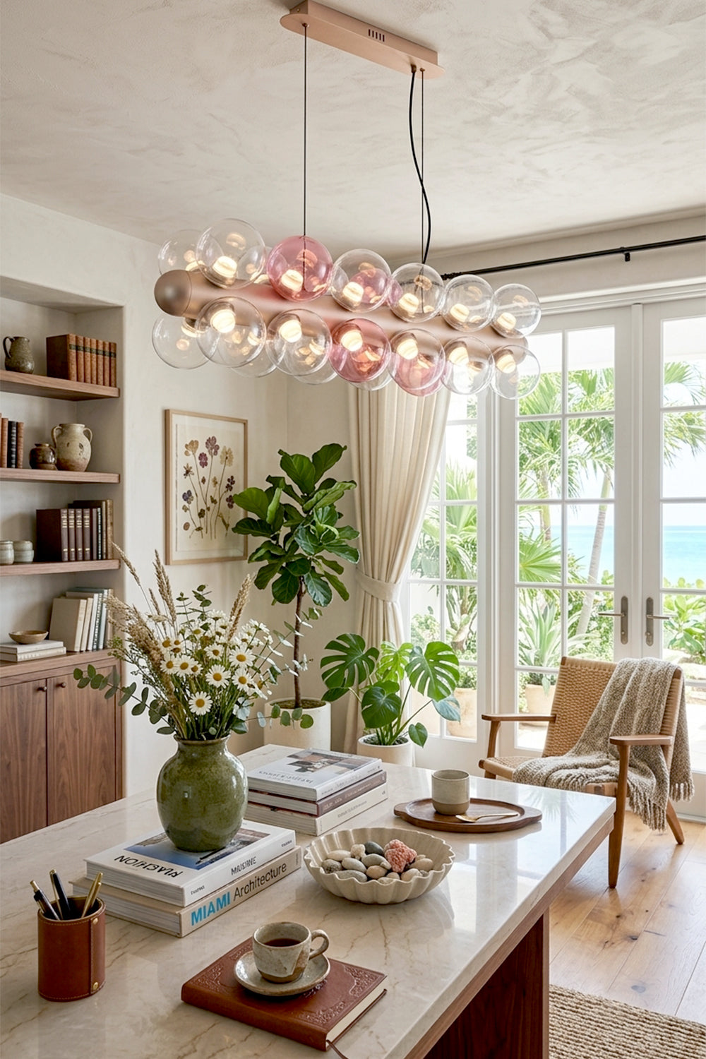 Astraea Linear Prismatic Globe Chandelier in modern dining room with plants and ocean view.