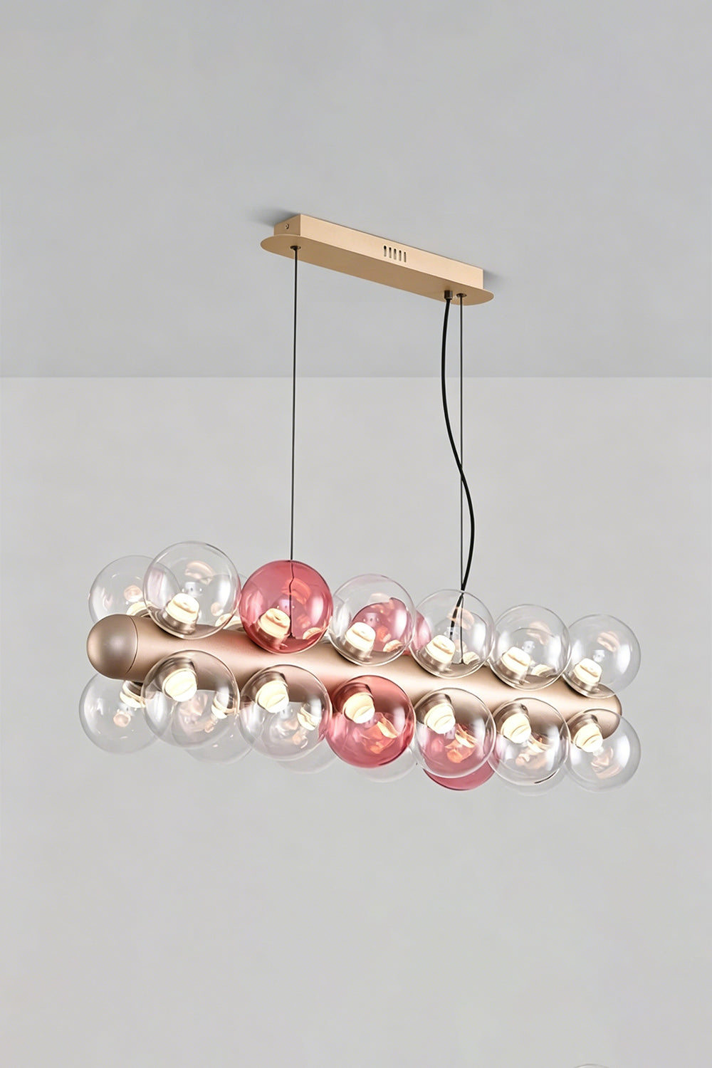 Astraea Linear Prismatic Globe Chandelier with hand-blown glass spheres in pink and clear, perfect for modern dining spaces.