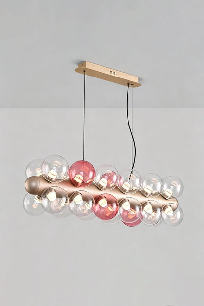 Astraea Linear Prismatic Globe Chandelier with hand-blown glass spheres in pink and clear, perfect for modern dining spaces.
