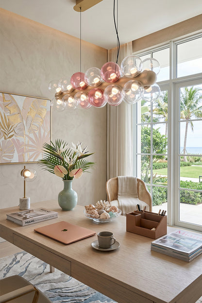 Astraea Linear Prismatic Globe Chandelier hanging over a stylish desk in a modern, bright interior with natural light.