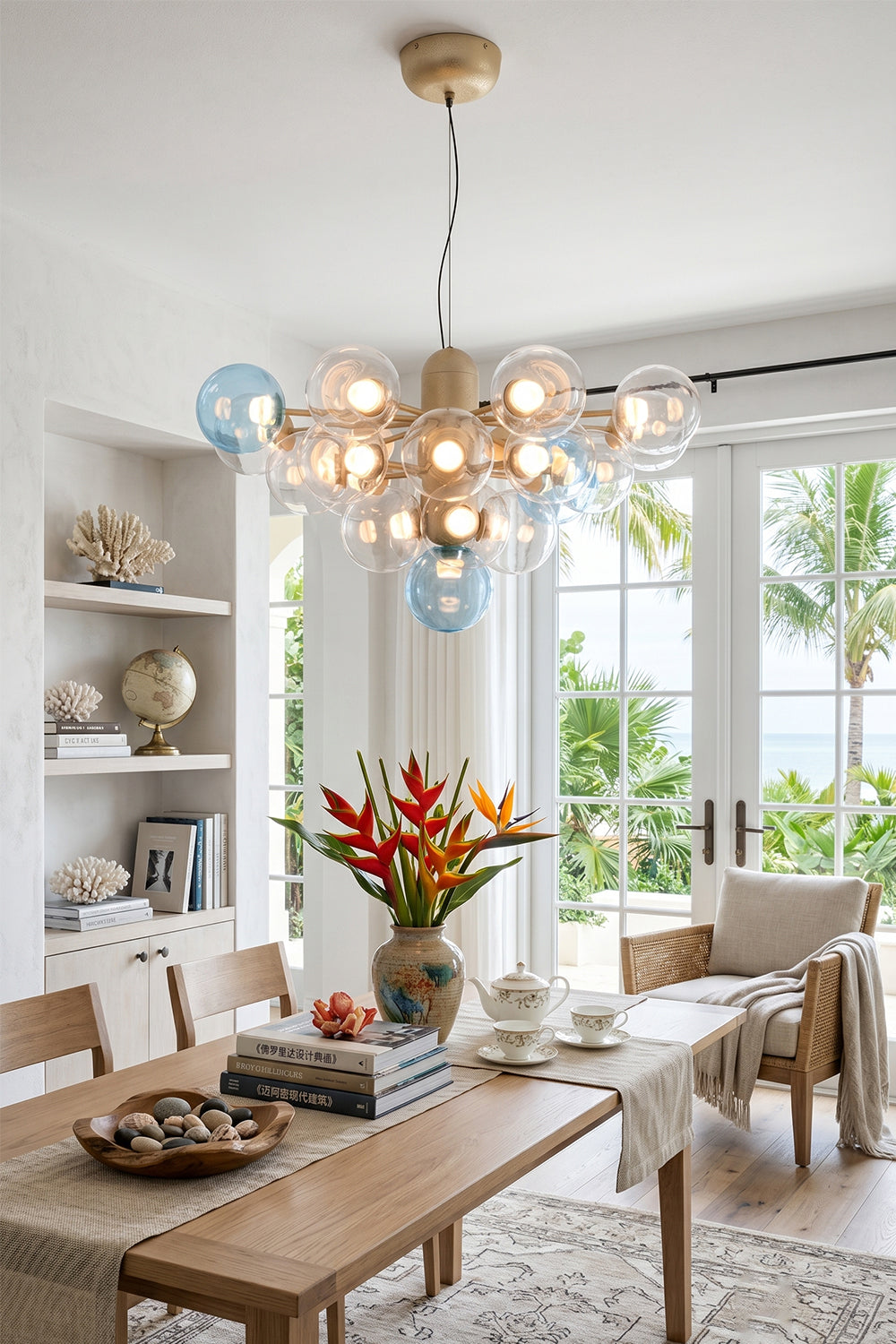 Astraea Prismatic Globe Chandelier | Glass, Metal | Illuminating a bright tropical-style dining room over a wooden table set near large sliding glass doors opening to a garden | vexa lamps
