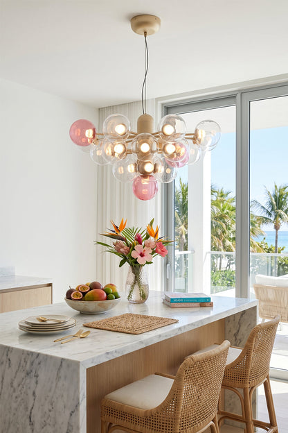 Astraea Prismatic Globe Chandelier | Glass, Metal | Suspended as a playful elegant centerpiece above a pristine white kitchen island counter with woven rattan bar stools in a coastal home | vexa lamps