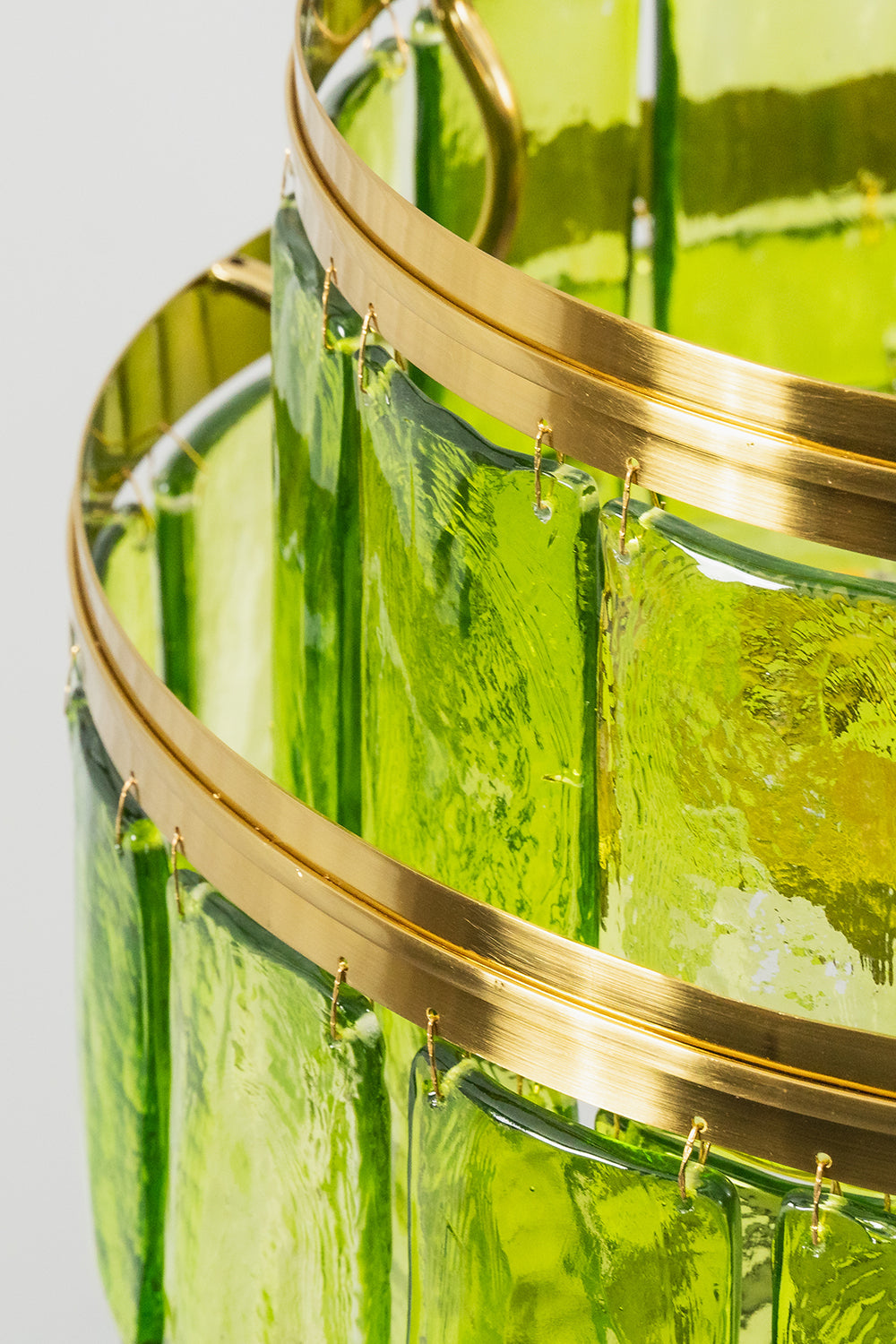 Aura Verdant Tiered Green Glass Ceiling Light | Metal, Glass | Close-up side profile of the brushed gold metal bands and the hooked green glass plates | Detail shot | vexa lamps