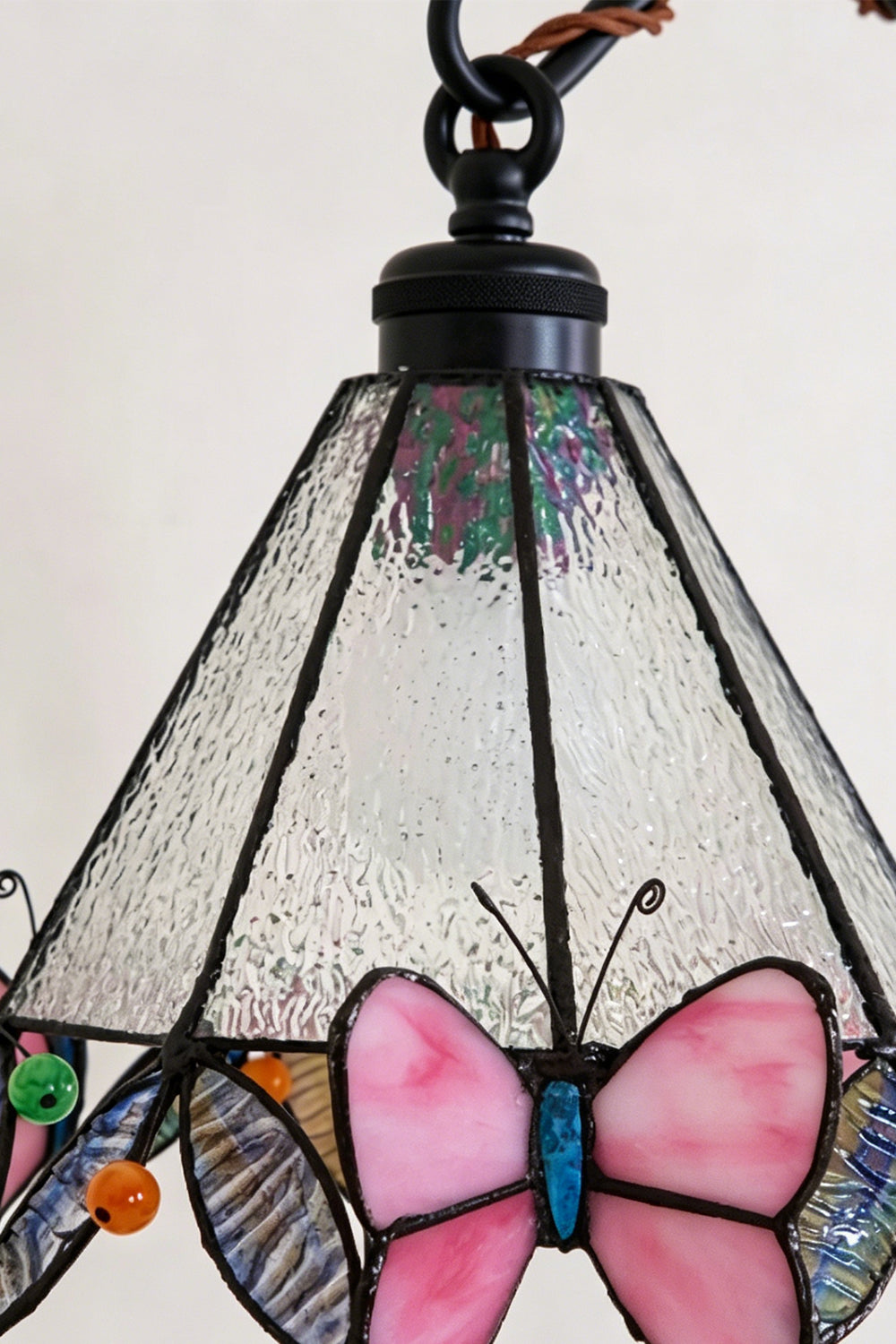 Aura Vine Stained Glass Wall Sconce | Glass, Metal | Close-up view of the unlit mosaic stained glass shade showcasing the intricate leading lines and pink butterfly trim | Detail shot | vexa lamps