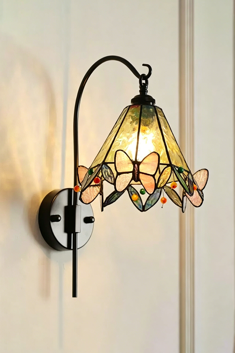 Aura Vine Stained Glass Wall Sconce | Glass, Metal | Frontal angled view of the fully lit lamp radiating soft light against a neutral plain wall | Isolated shot | vexa lamps