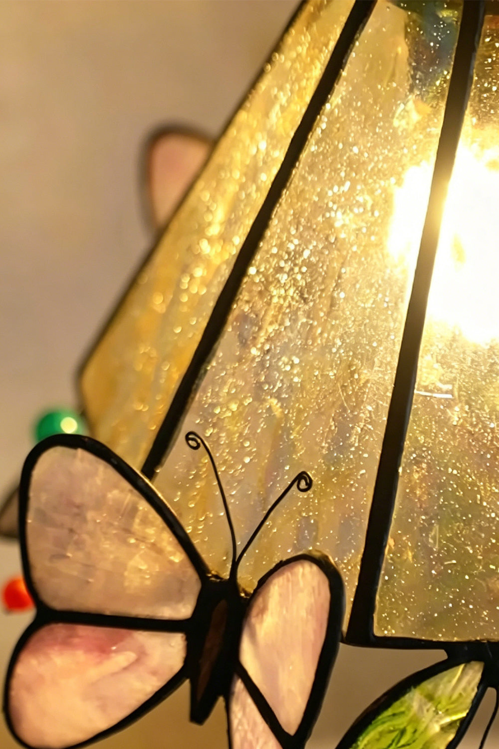 Aura Vine Stained Glass Wall Sconce | Glass, Metal | Macro close-up of the lit textured glass panel and a translucent pink butterfly wing element under warm backlighting | Detail shot | vexa lamps