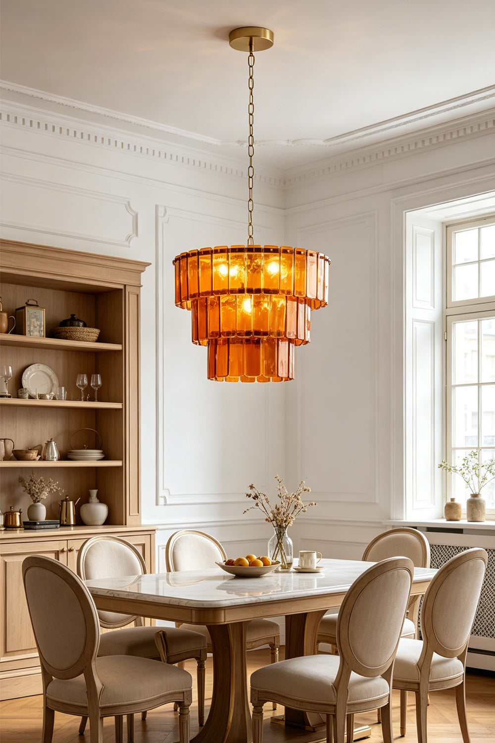 Aurelia Tiered Amber Glass Chandelier illuminating a modern dining space with warm, golden light.
