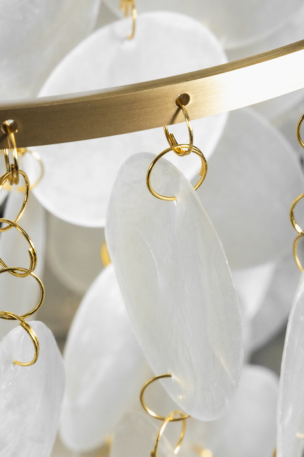 Aurelia Tiered Capiz Table Lamp | Capiz Shell, Metal | Detailed close-up showing the translucent capiz shell discs hanging from gold metal loops on the circular frame | Detail shot | vexa lamps