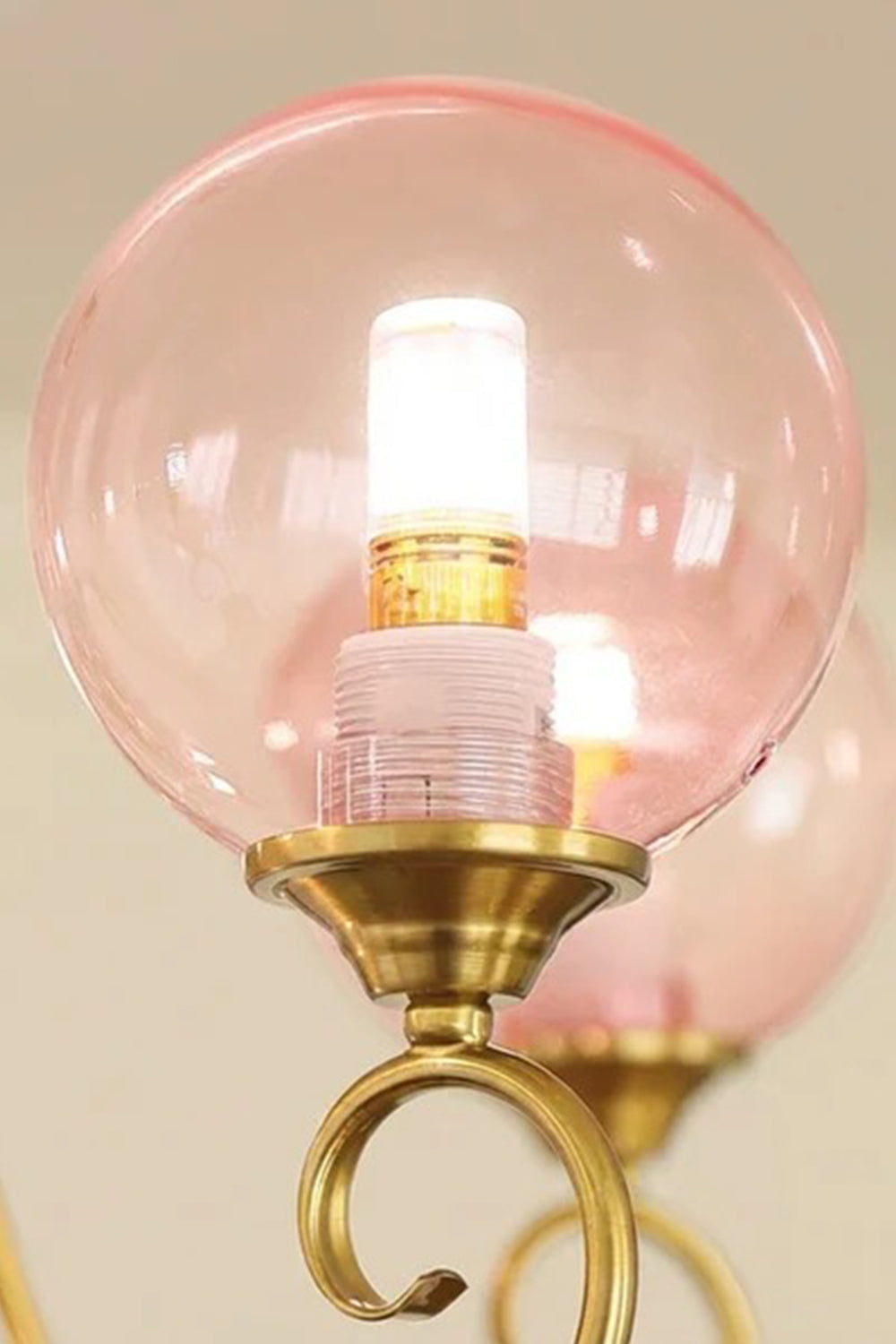 Aveline Globe Cluster Chandelier | Colored Glass and Brass | Macro detail shot of an illuminated pink glass sphere on a brass stem | vexa lamps