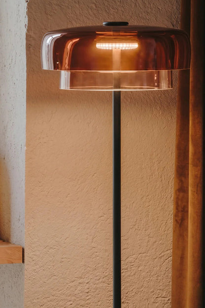 Aven Minimalist Architectural Floor Lamp | Glass, Metal | Close-up shot of the amber glass shade variant casting a warm golden glow against a textured neutral wall | Detail shot | vexa lamps