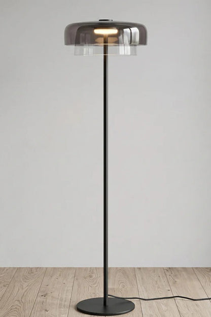 Aven Minimalist Architectural Floor Lamp | Glass, Metal | Studio front view of the fully illuminated smoky grey glass floor lamp variant displayed on a clean wooden floor | vexa lamps