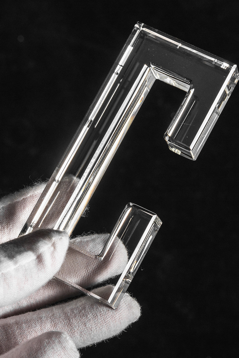 Aven Tiered Glass Prism Chandelier | Glass, Metal | A gloved hand holding a single clear molded rectangular glass link prism hook to showcase size and texture | Detail shot | vexa lamps