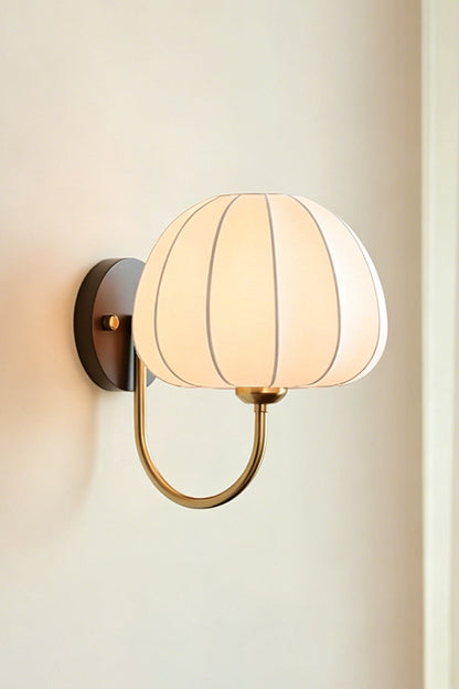 Baird Mid Century Pumpkin Wall Lamp | Metal, Fabric, Wood | Frontal angled view of the fully lit lamp radiating soft light against a neutral plain wall | Isolated shot | vexa lamps