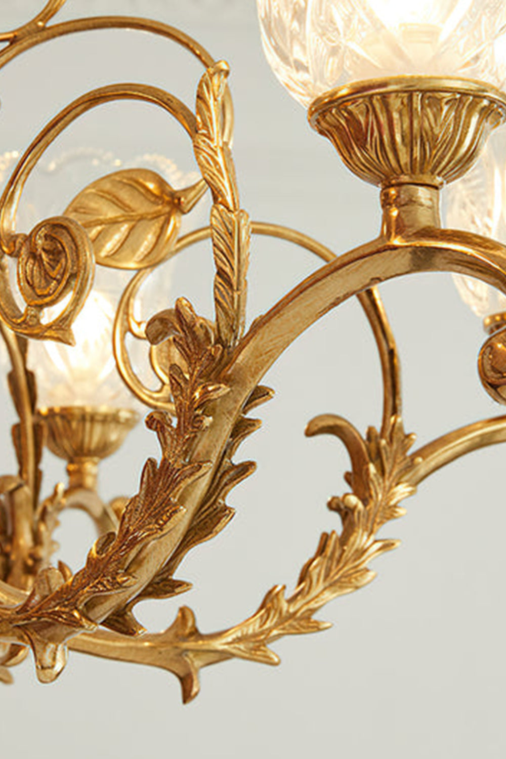 Beatrix Acanthus Leaf Chandelier | Ornate Brass and Frosted Carved Glass | Detailed shot of the intricate acanthus leaf relief and baroque scrollwork along the polished gold arms | vexa lamps