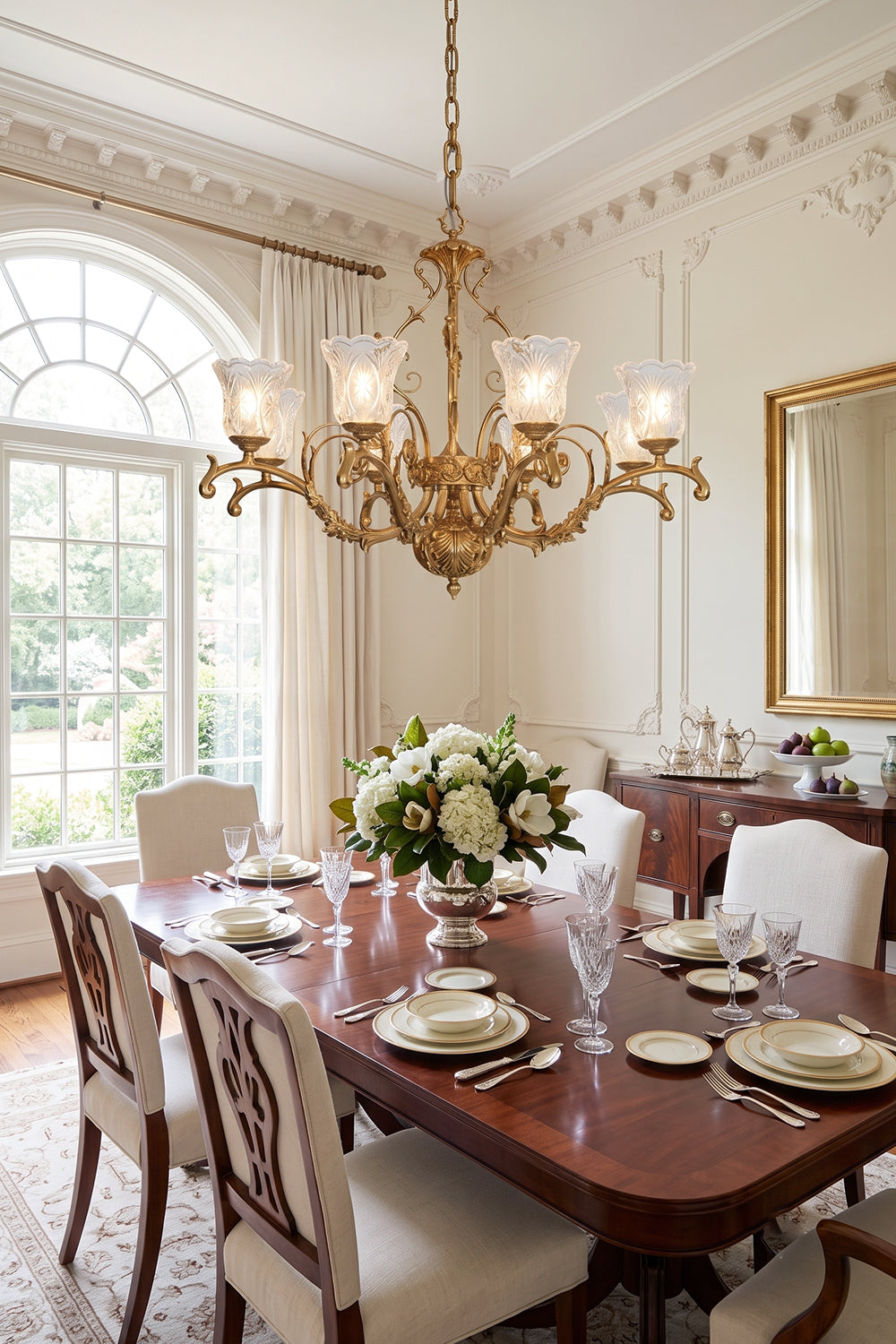 Beatrix Acanthus Leaf Chandelier | Ornate Brass and Frosted Carved Glass | Positioned over a long mahogany dining table with high-backed upholstered chairs next to a large arched window | vexa lamps